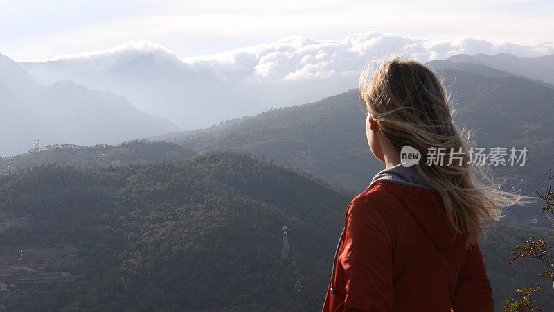 日出时，女徒步旅行者在山坡上休息