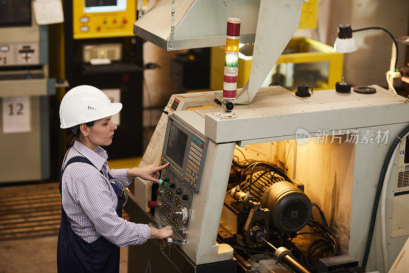 女技术工程师在工厂选择数控加工操作时，会站在数控车床前，按下按钮