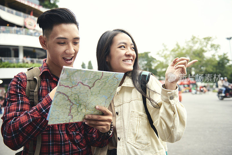 一对亚洲夫妇在街上用纸质地图