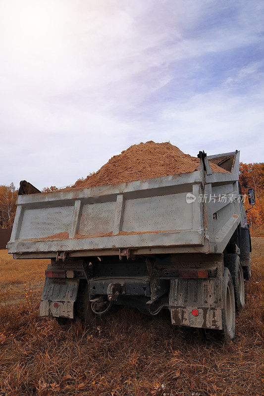 一辆自卸卡车在建筑工地卸沙子。