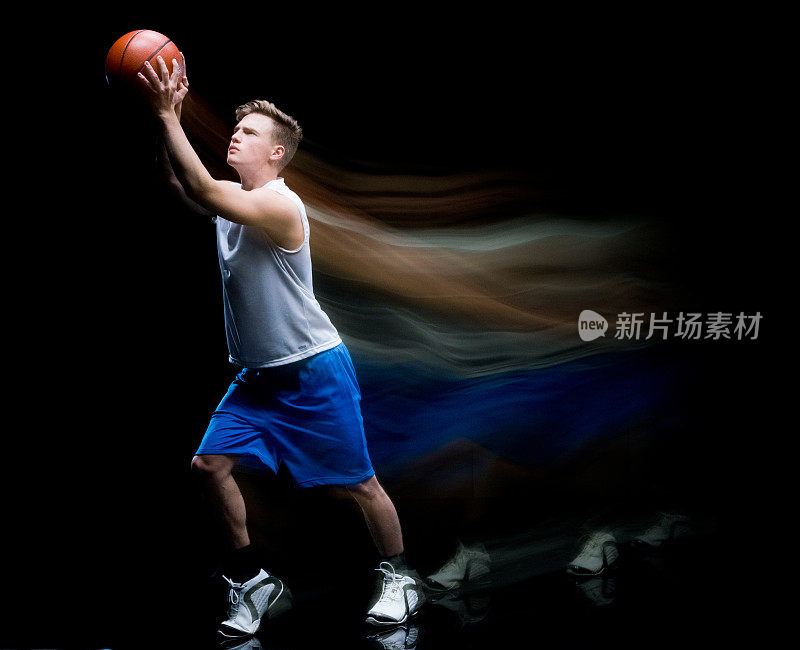 白人男性无袖在黑色背景前模糊运动穿着短裤，拿着篮球和使用运动球