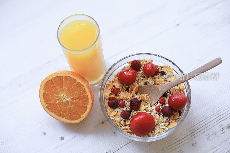 格兰诺拉麦片早餐配新鲜的红莓、橙、榛子和橙汁