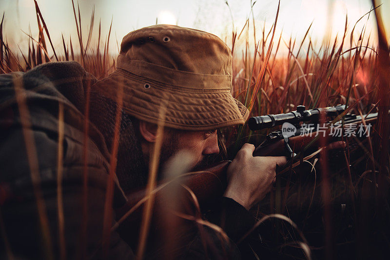 猎人躺在长长的红草地上看着他的狙击手
