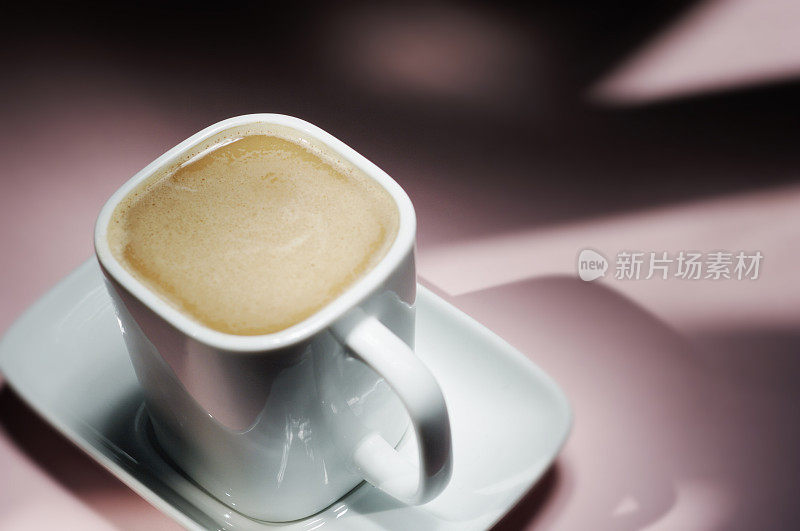 一杯浓郁的白咖啡映衬着粉红色的背景