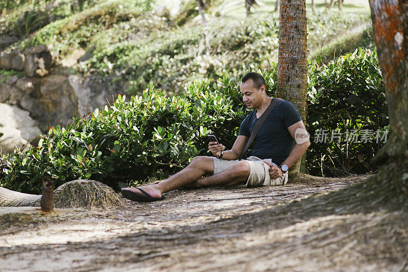 一个西班牙男人在海滩上发短信