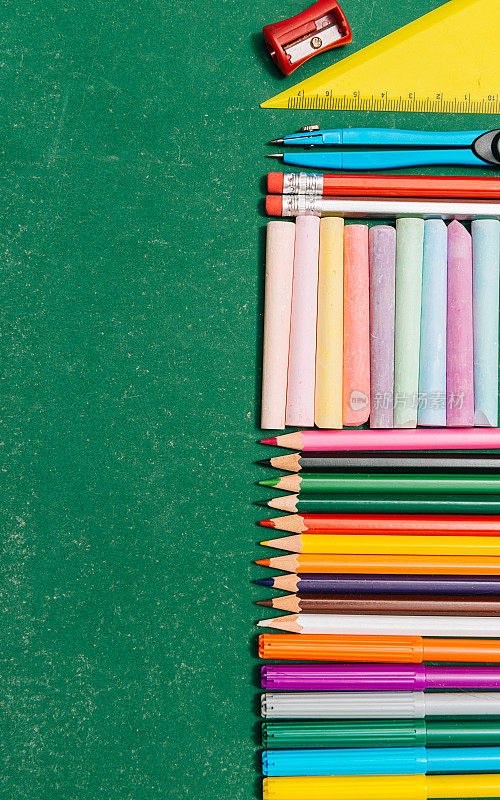学校物品，铅笔，蜡笔和隔板在空的学校黑板上