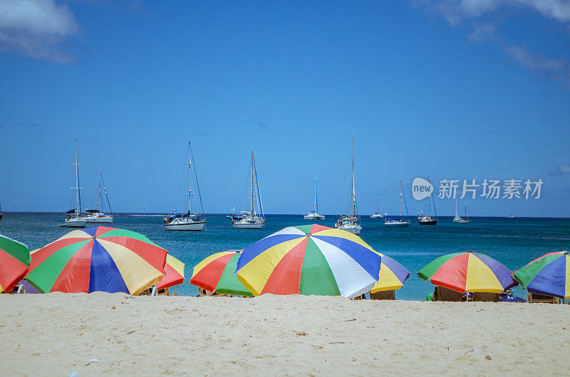 豪华的加勒比海滩上有游艇和五颜六色的雨伞