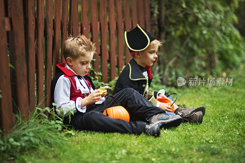 万圣节期间，小男孩们坐在草地上吃糖果