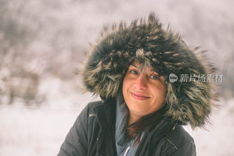 冬天的女人在寒冷的冬日里，在雪地里仰望着快乐的微笑。