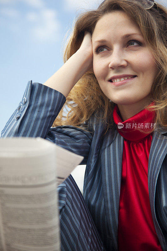 女商人坐在户外看报纸