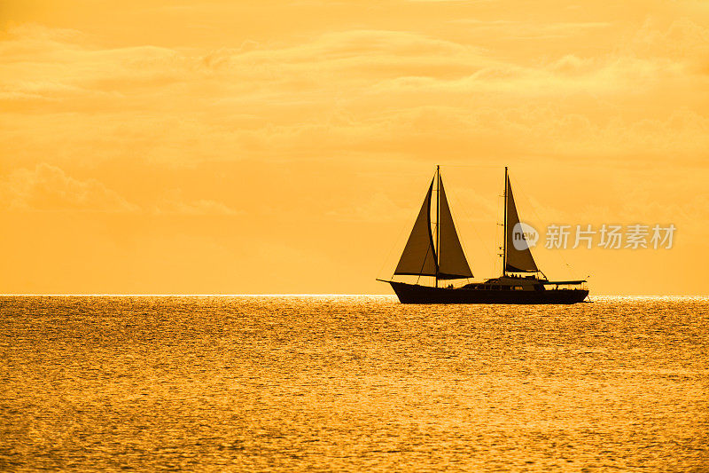 日落时平静海面上的帆船