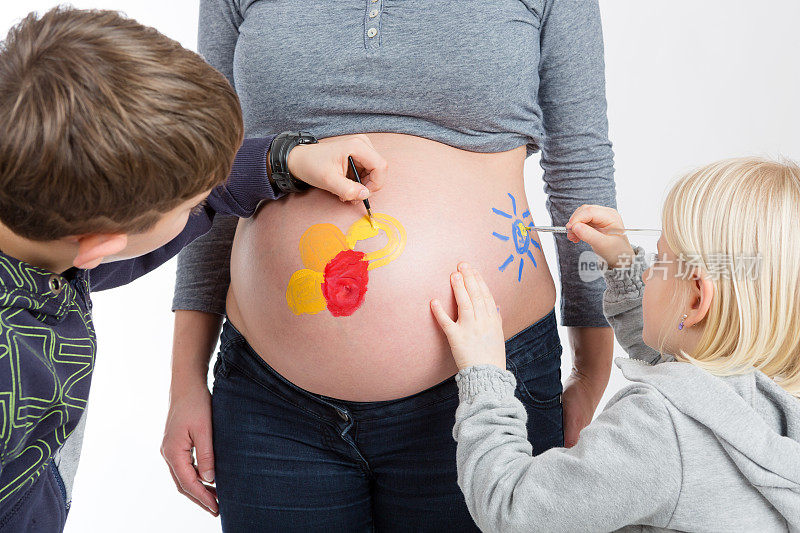 孩子们在他们怀孕的母亲的肚子上画画