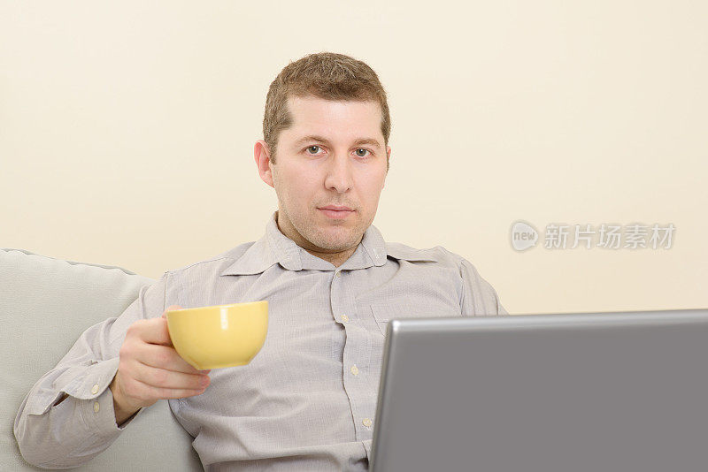 一边喝着咖啡一边用笔记本电脑工作的人