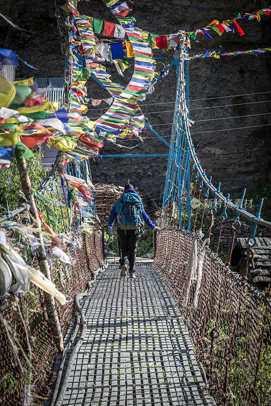 尼泊尔Annapurna徒步旅行者穿过一座吊桥