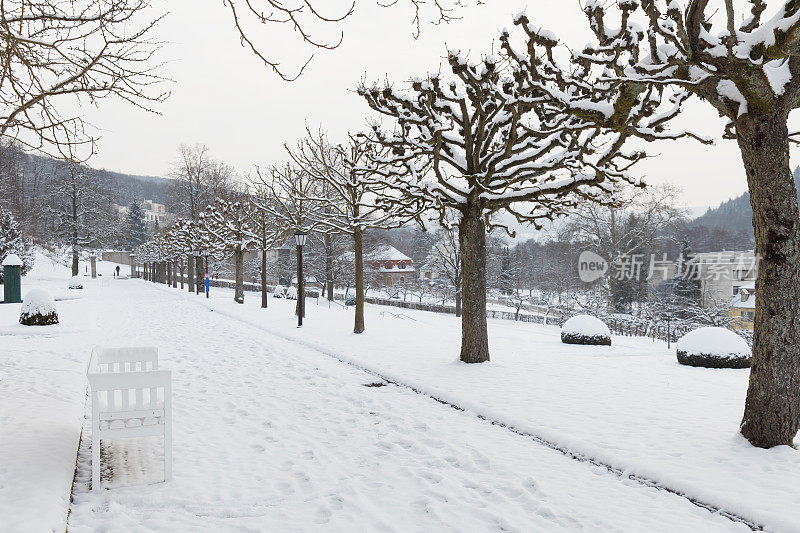皑皑白雪覆盖着公园冬季长凳和别墅栈道