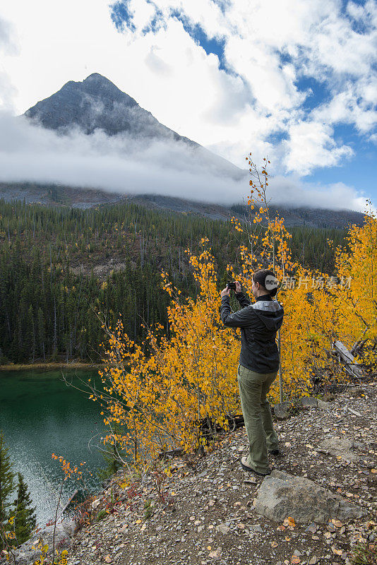 秋天，徒步者在山林中拍摄湖泊的照片