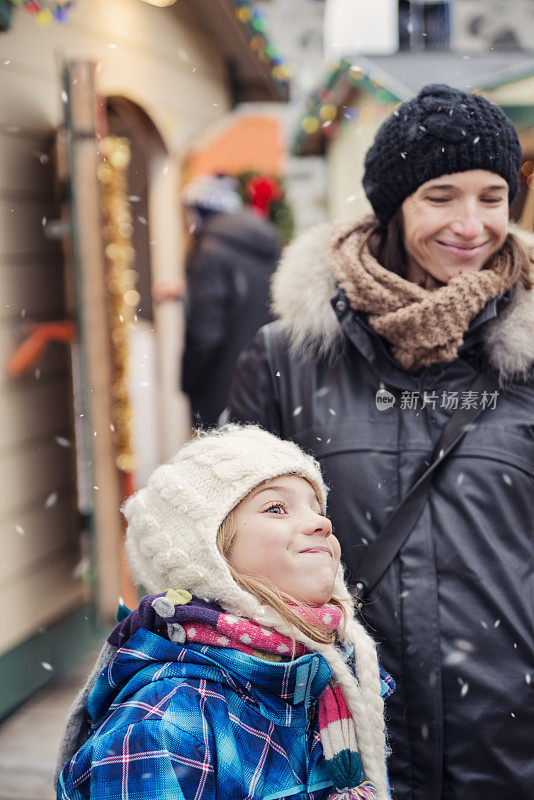 表情丰富的小女孩和妈妈在公共市场购物，冬天。