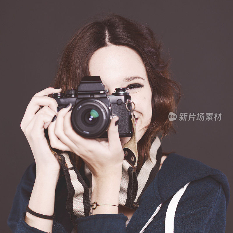 一位年轻女子正在用复古相机拍照。
