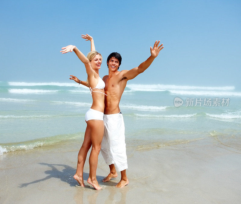 海滩上一对年轻夫妇的手在空中举起