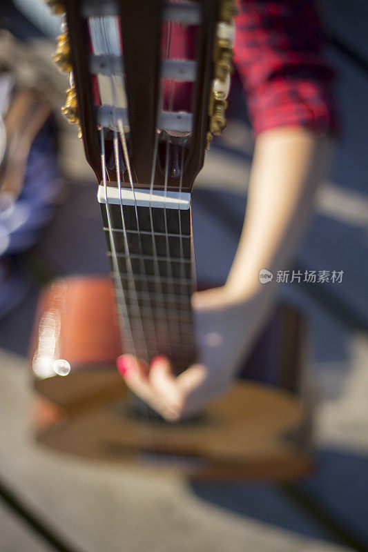 年轻女子坐在码头上弹吉他
