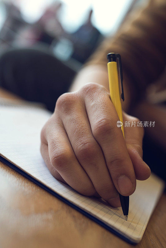 近距离观察一个面目全非的人在笔记本上写字。