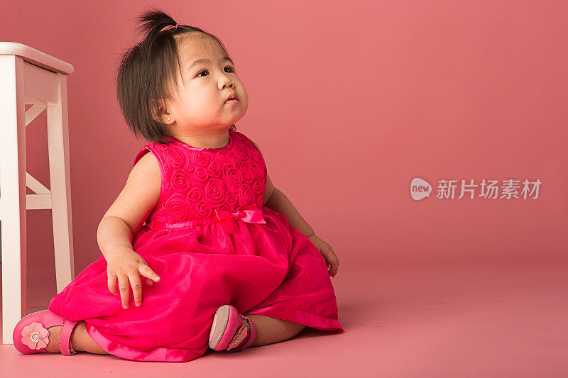 亚洲幼童坐在粉红色的背景