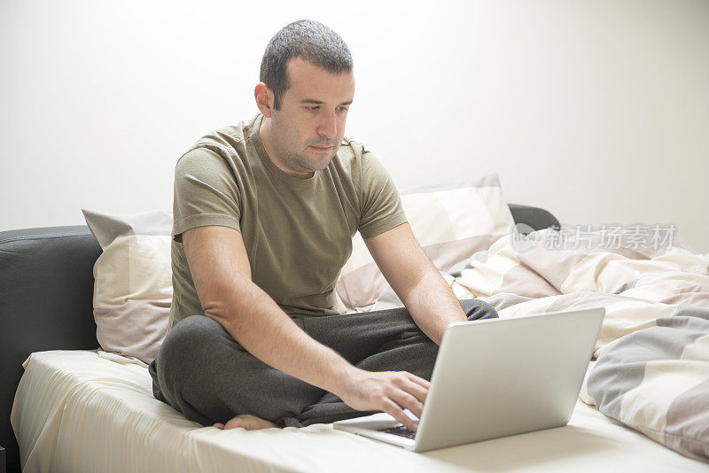 一个男人在床上用笔记本电脑