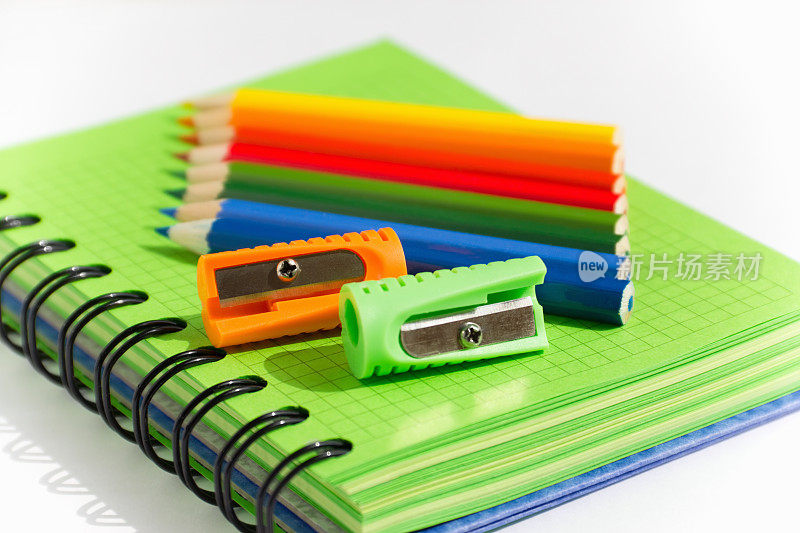 绿色笔记本，彩色铅笔和卷笔刀