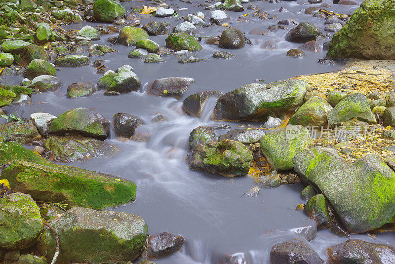 在绿色的长满苔藓的岩石之间的暗色水流