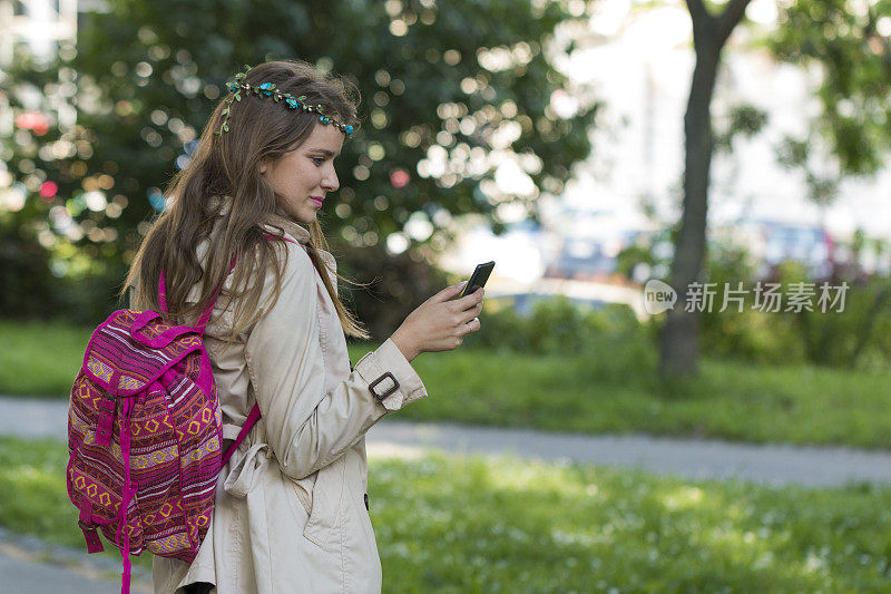一个好女孩正在公园里散步，正在用手机写短信