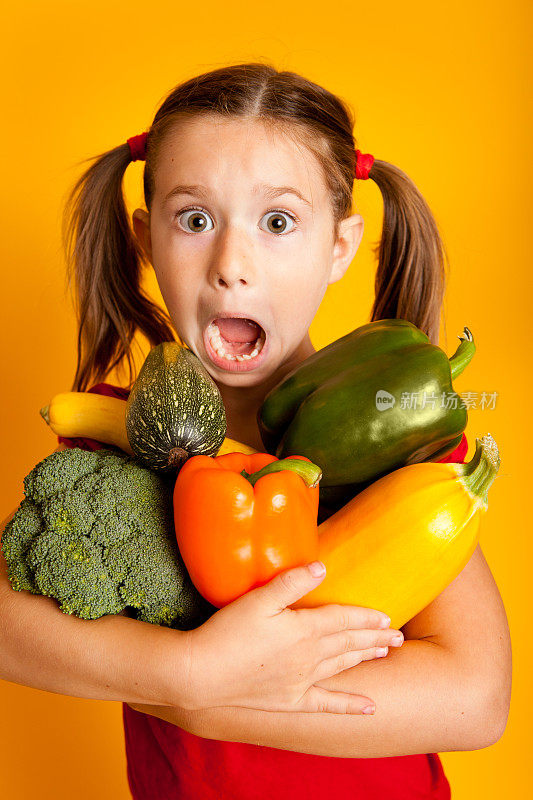 震惊的小女孩拿着蔬菜，青椒，花椰菜，南瓜，西葫芦