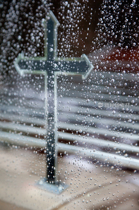 灵车上的十字架和窗玻璃上的雨滴