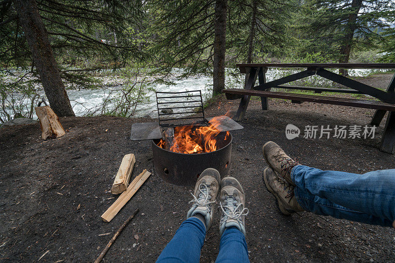 年轻夫妇在营地的火边放松