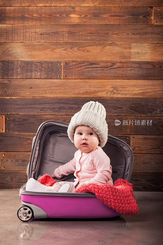 可爱的婴儿在粉红色的旅行袋