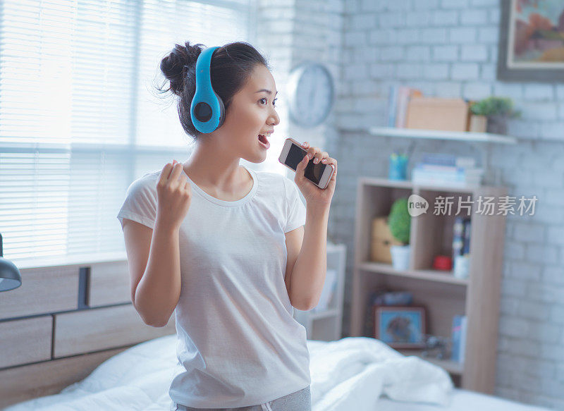 亚洲妇女正在听音乐，她在房间里唱歌。幸福的