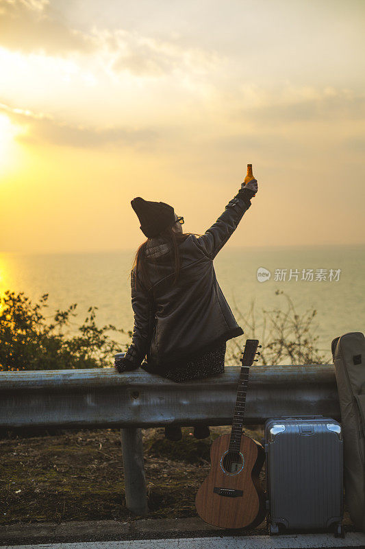 夕阳西下，年轻女子喝着啤酒