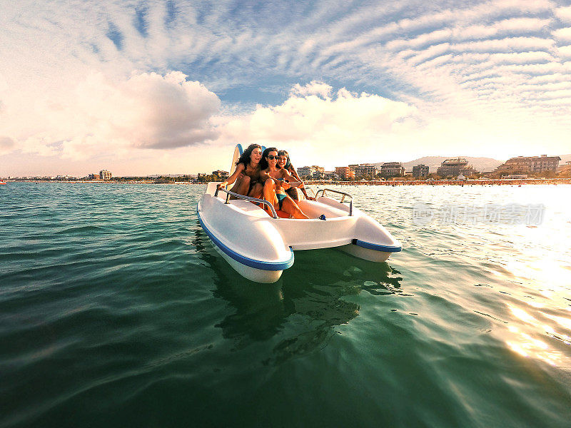 三个年轻女子在脚踏船上享受夏天