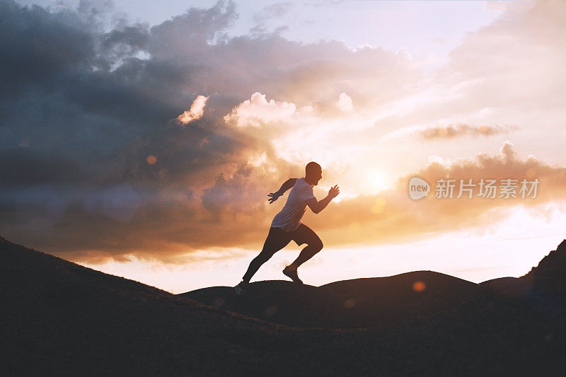 日落时分，运动员在户外的山丘上快速奔跑。健康的生活方式的概念