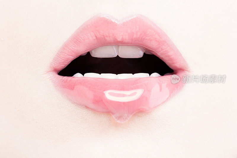 女性用粉色唇彩。用化妆品和唇彩润湿嘴唇