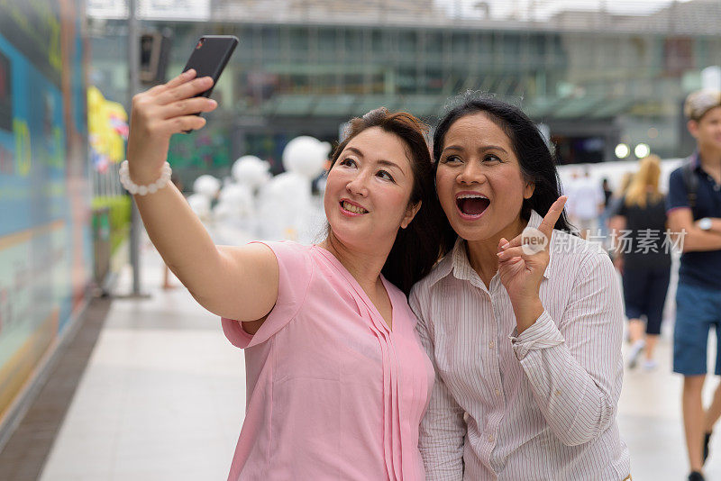 两个成熟的亚洲女性朋友在泰国曼谷购物中心外的肖像