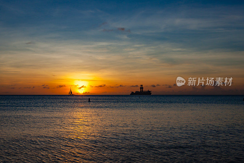 加勒比海阿鲁巴岛西海岸的日落。地平线上的船和石油勘探船的剪影