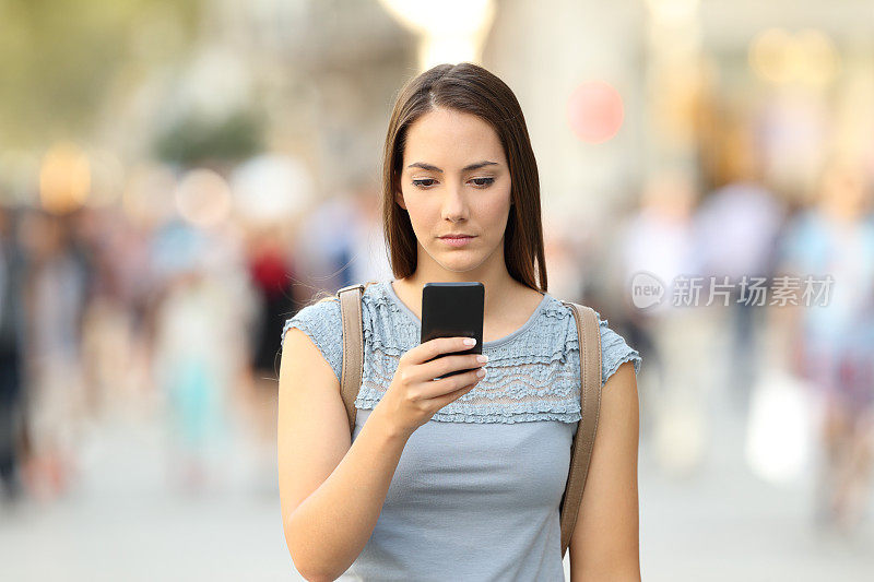 严肃的女孩在街上查看手机留言