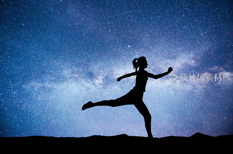 黎明时分，一个体育女孩正在练瑜伽。星空下的健身课