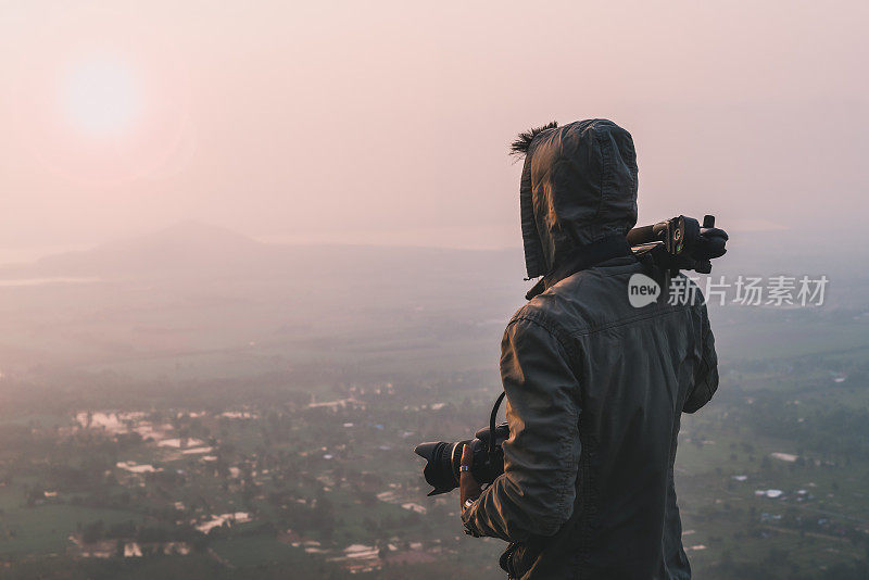 旅行者摄影师和照相机在山上拍照早晨太阳升起。旅行生活爱好概念