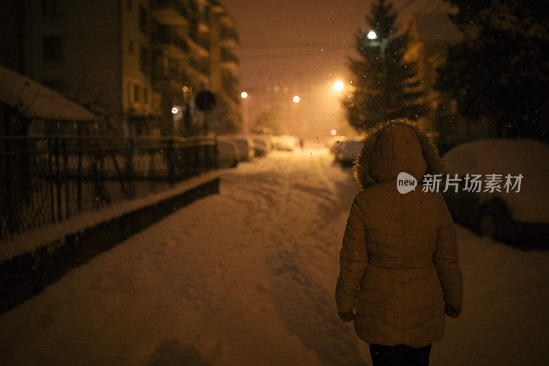 一个女人在下雪的晚上散步