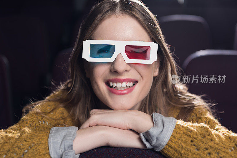 戴着3d眼镜，面带微笑的年轻女子在电影院看电影