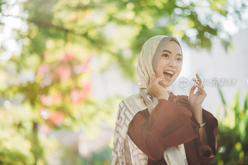 一幅亚洲年轻的马来人戴着头巾的女性兴奋的画像