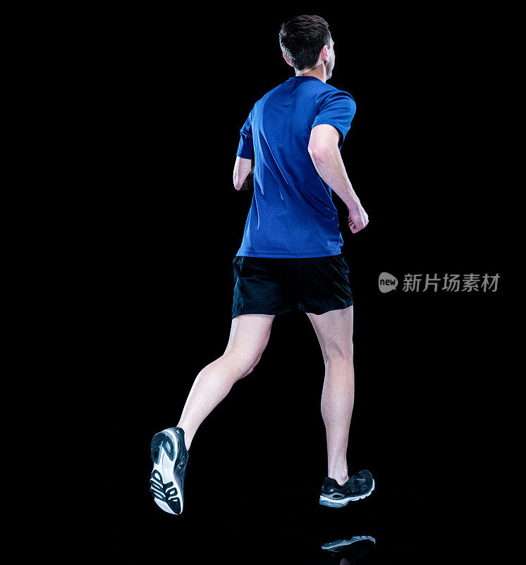 穿着运动鞋在黑色背景前慢跑的白人年轻男性运动员