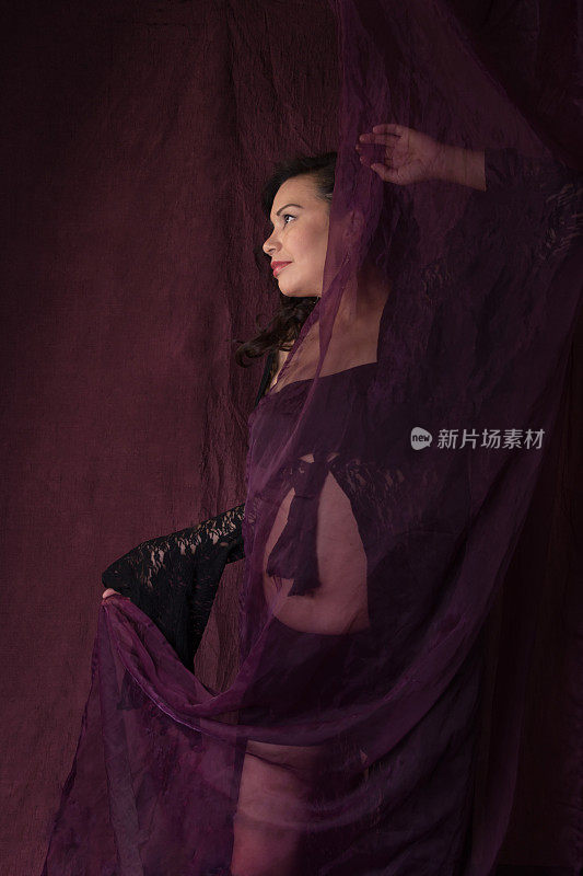 怀孕的加拿大土著妇女在黑色蕾丝长袍跳舞与透明的紫色织物。