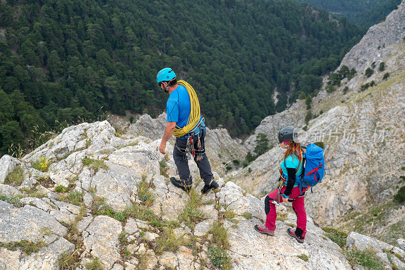高山登山队正在一座山峰的岩壁上行走